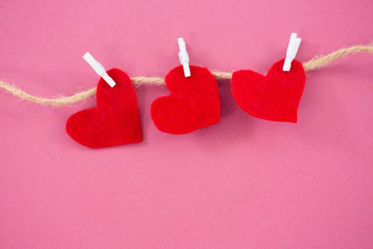 Red hearts with cloth peg hanging on rope