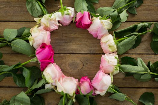 Pink roses arranged in round shape on wooden plank