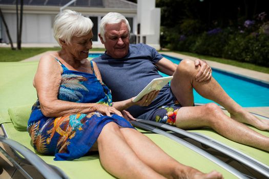Senior couple looking at digital tablet on lounge chair