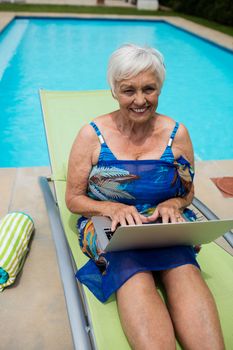Portrait of senior woman using laptop on lounge chair