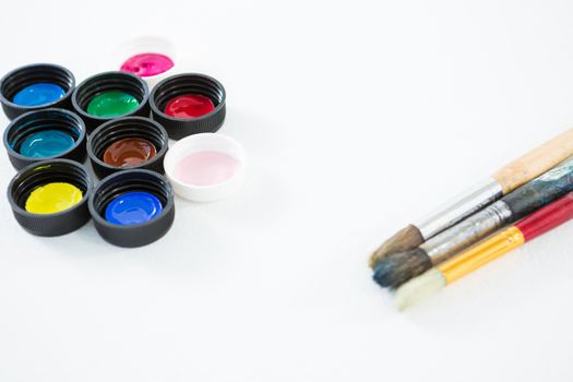 Colorful lids and paintbrushes on white background
