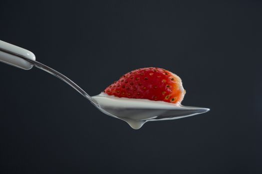 Close-up of fresh strawberry with cream in spoon