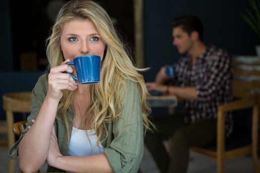 Young woman drinking coffee at cafeteria