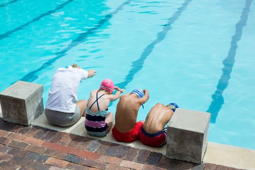 Swimming instructor teaching students at pool side