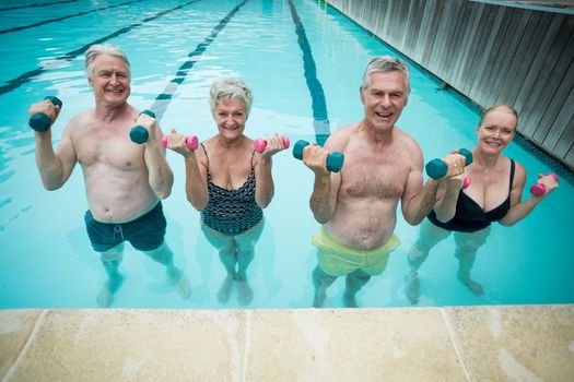 Happy swimmers weightlifting in swimming pool
