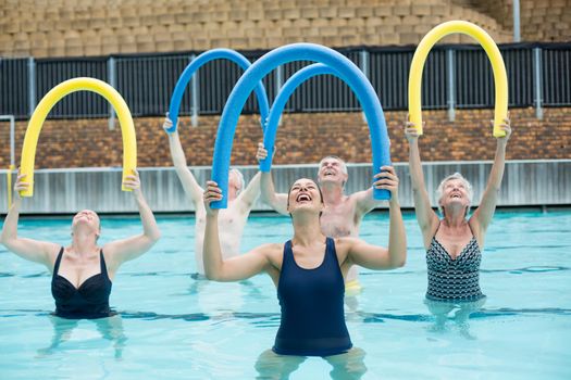 Happy trainer and senior swimmers exercising in swimming pool