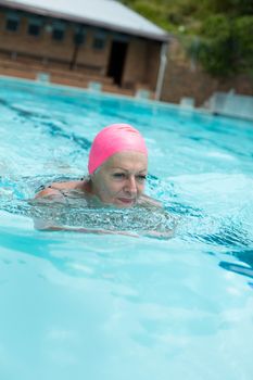 Senior woman wearing cap while swimming in pool