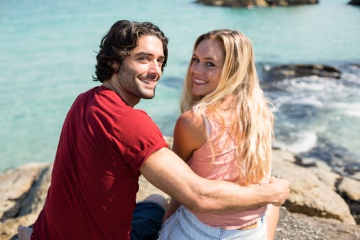 Happy young couple with arm around on rock