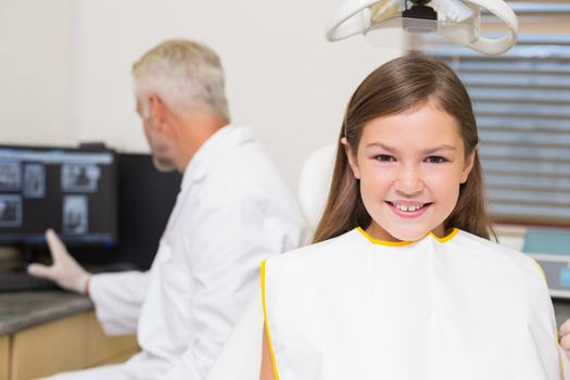 Smiling little girl looking at camera in dentists chair