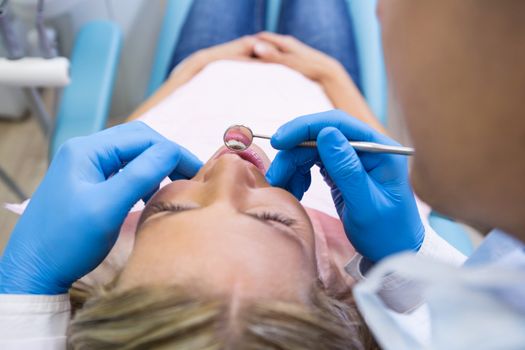 Patient lying on bed while dentist examining at clinic