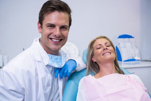 Portrait of smiling patient and dentist sitting on chair