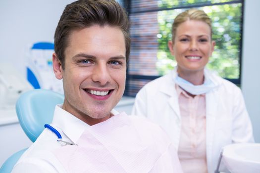 Smiling man and dentist sitting at dental clinic