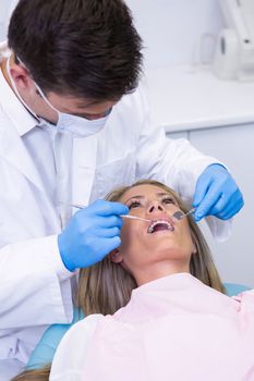 Close up of dentist holding equipment while examining woman