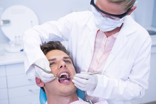 Dentist examining man mouth at medical clinic