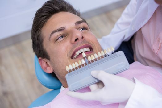 Dentist holding equipment while examining man at medical clinic