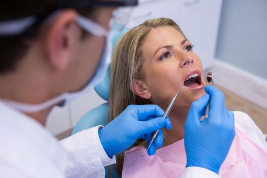 Dentist examining woman mouth at clinic