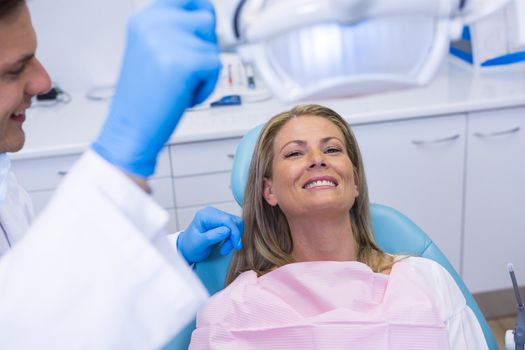 Dentist adjusting electric light while patient sitting on chair