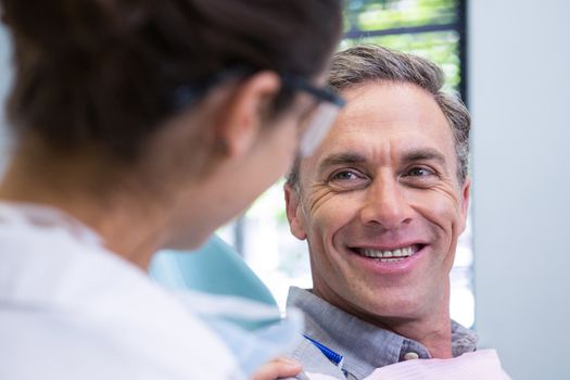 Closeup of happy patient looking at dentist in medical clinic