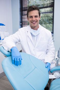 Portrait of dentist standing by chair