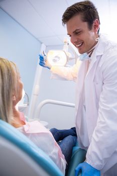 Dentist adjusting lamp while looking at patient in clinic