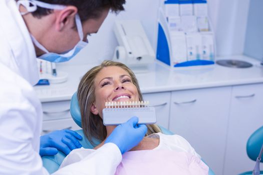 Doctor holding tooth whitening equipment by smiling patient