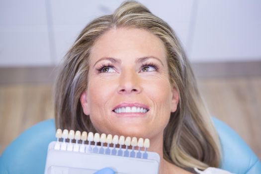 Extreme close up doctor holding tooth whitening equipment by smiling patient