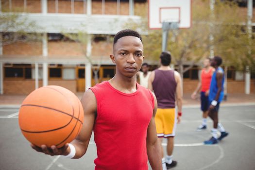 Male basketball player holding basketball in basketball court