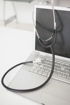 Stethoscope draped over silver laptop on desk in an office