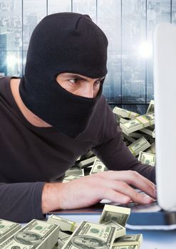 Criminal in balaclava with laptop and money in front of window