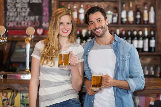 Young friends holding beer at pub