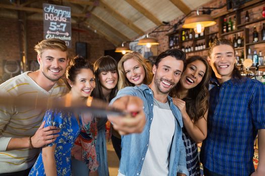 Happy friends taking selfie in pub