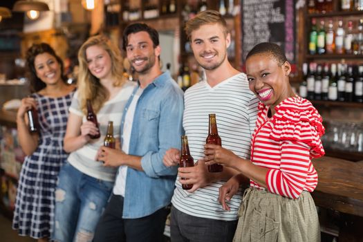 Cheerful friends with beer bottles at pub