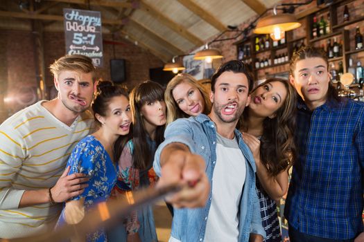 Cheerful friends taking selfie in pub