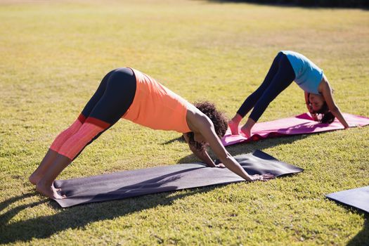 Girl practicing downward facing dog positiong with trainer