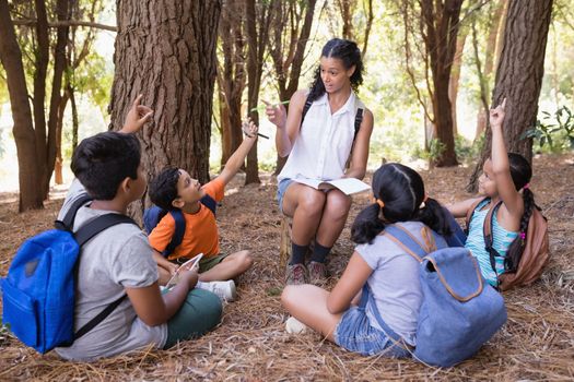 Teacher explaning students sitting in forest