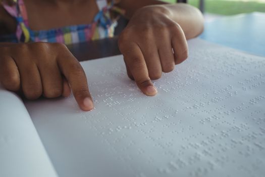 Cropped hands of girl reading braille