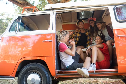 Happy friends sitting together in camper van