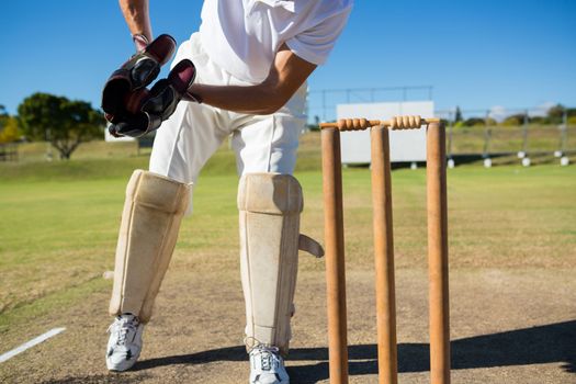 Low section of wicket keeper standing by stumps during match