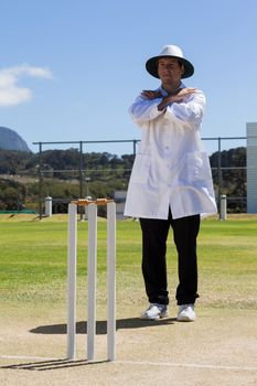 Full length of cricket umpire signaling cancel call sign during match