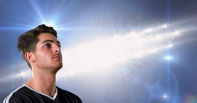 Soccer player looking away against floodlight