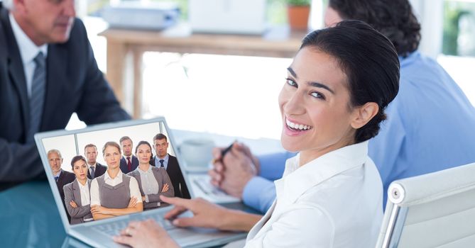 Smiling businesswoman video conferencing with colleagues in office