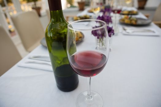 Red wineglass and bottle on dining table at restaurant