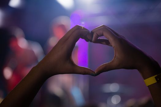Hands of audience forming heart shape during stage show