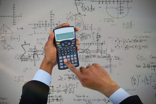 Composite image of cropped hands of businessman using calculator 