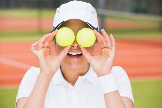 Pretty tennis player holding balls over her eyes