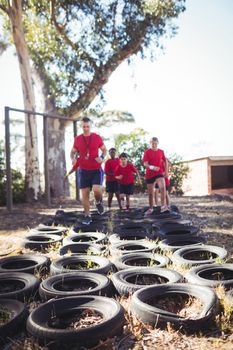 Trainer instructing kids during tyres obstacle course training