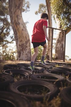 Boy running over tyres during obstacle course