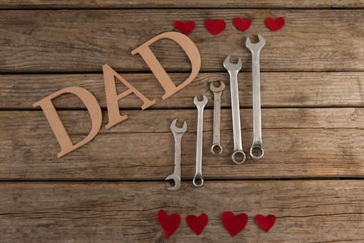Dad text by wrenches and heart shapes on table