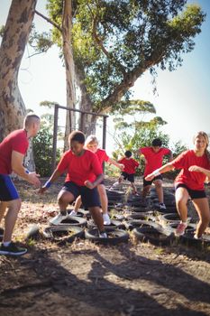 Trainer instructing kids during tyres obstacle course training
