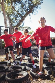 Kids running over tyres during obstacle course training